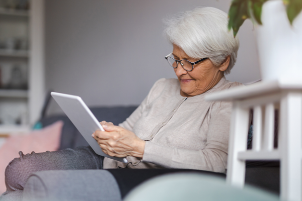 Elderly woman sitting in chair, using a tablet